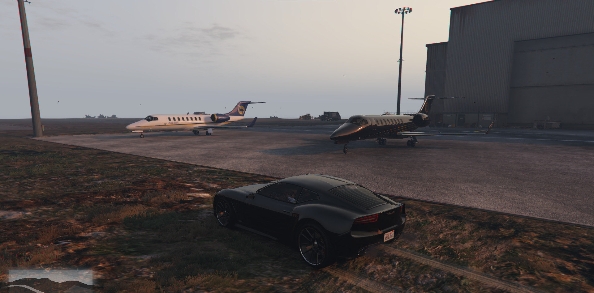 A screenshot of a car in front of several private jets in GTA 5